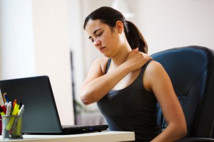 Female working at her desk with neck/shoulder pain